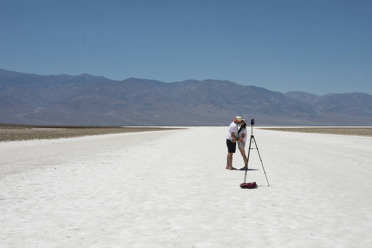 Tourists kiss at Badwater Basin on Monday, July 8, 2024, in Death Valley National Park, Calif. ...