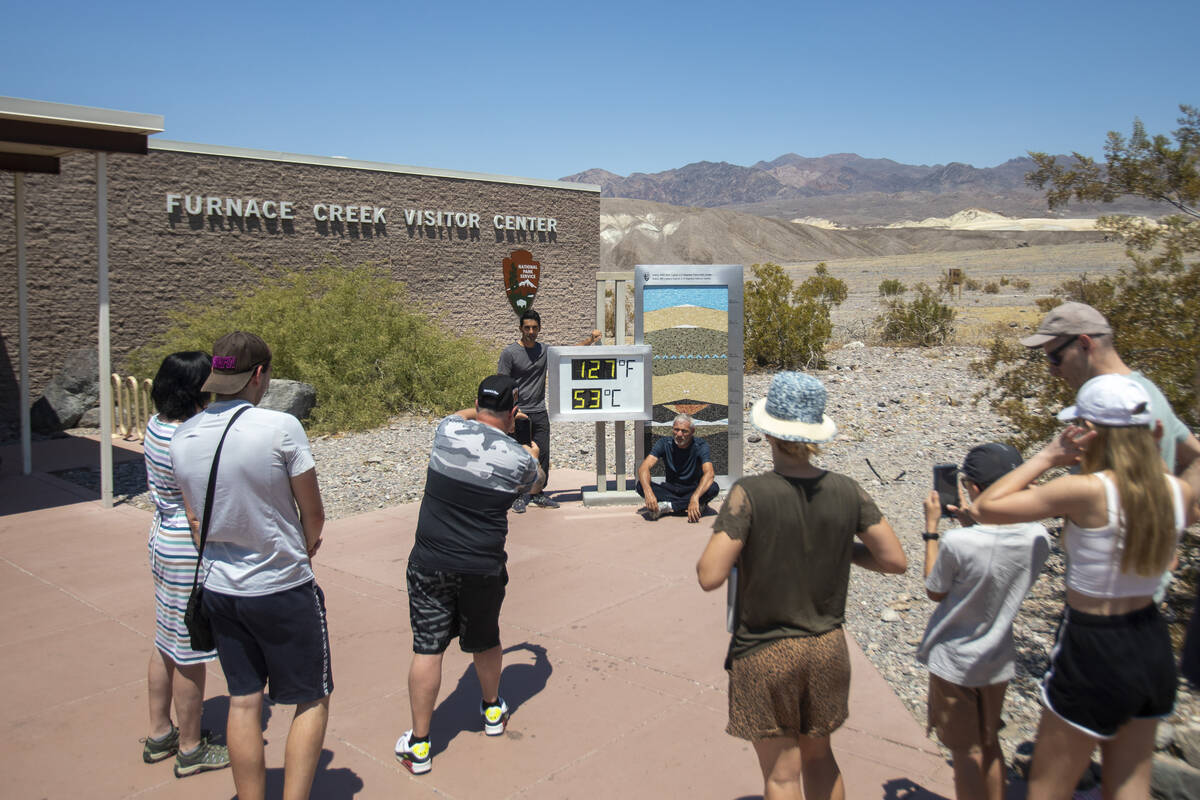 Tourists take photographs in front of the Furnace Creek Visitor Center thermometer on Monday, J ...