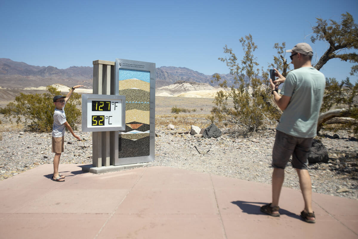 Tourists take photographs in front of the Furnace Creek Visitor Center thermometer on Monday, J ...