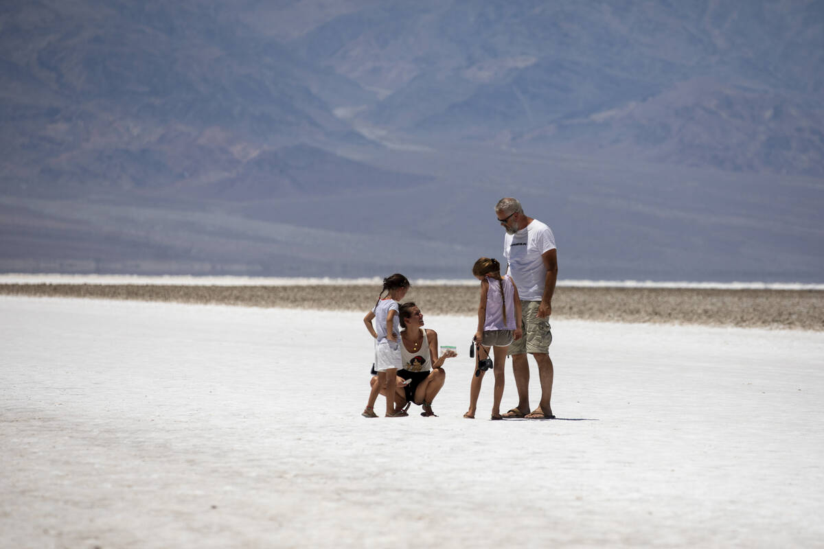 Tourists scoop salt from Badwater Basin into a plastic bag on Monday, July 8, 2024, in Death Va ...