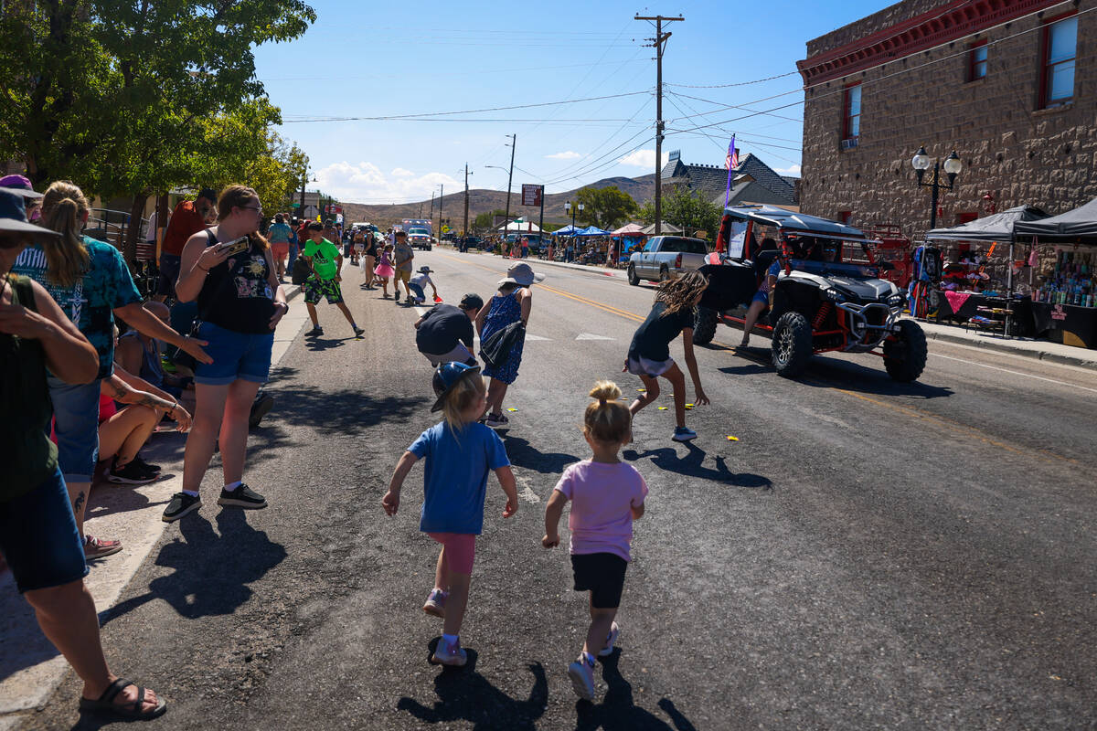 Children run to pick up candy during the Goldfield Days parade on Saturday, Aug. 3, 2024, in Go ...