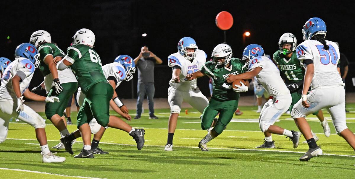 Anthoni Aguilar with the Beatty Hornet football team runs the ball in between Owyhee players in ...