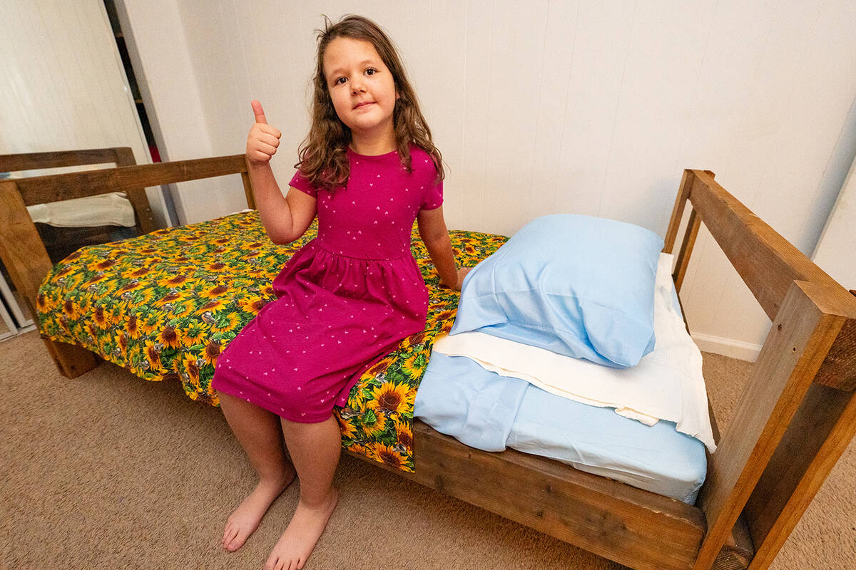 John Clausen/Pahrump Valley Times A young girl perches proudly on her brand new bed, provided b ...