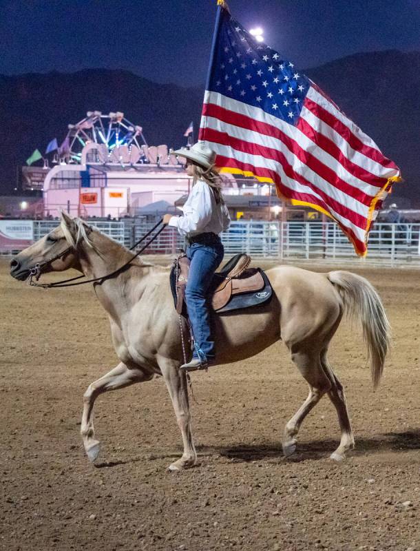 At the Pahrump Fall Festival 2024 a woman carries the U.S flag while riding on a horse on Satur ...