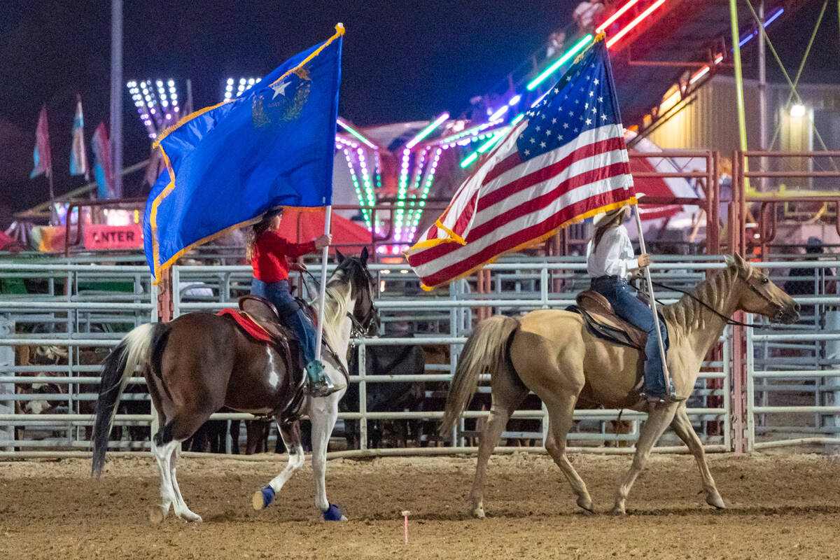 At the Pahrump Fall Festival 2024 a woman carries the U.S flag (right) and girl carries the Nev ...