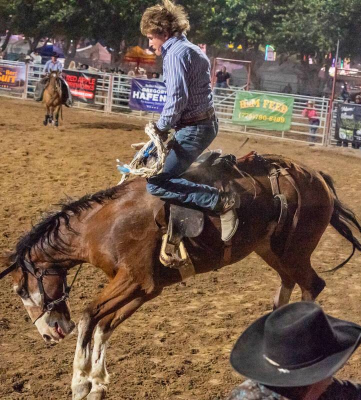 A man attempts to hold on as a horse tries to throw off the man from its back at the Pahrump Fa ...