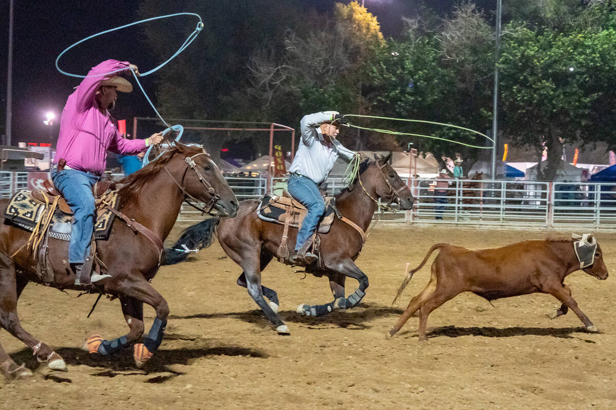 Two performers on horseback attempt to rope a calf at the at the Pahrump Fall Festival 2024 rod ...