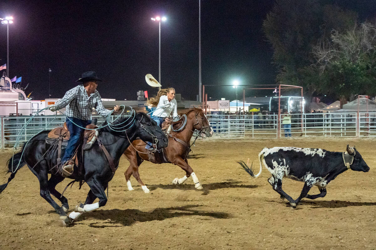 Two performers on horseback attempt to rope a calf at the at the Pahrump Fall Festival 2024 rod ...