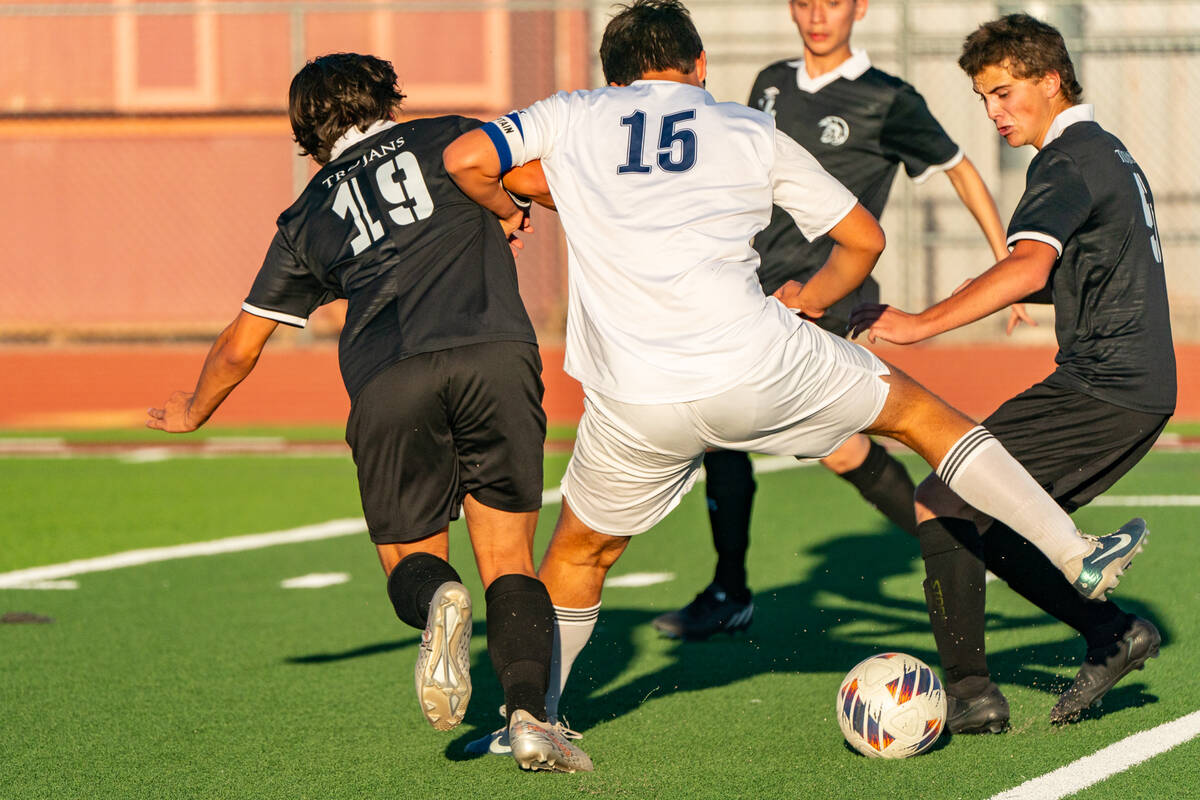 Trojans Mason Whitney (19) (left) attempts to take the ball away from The Meadows School on Tue ...