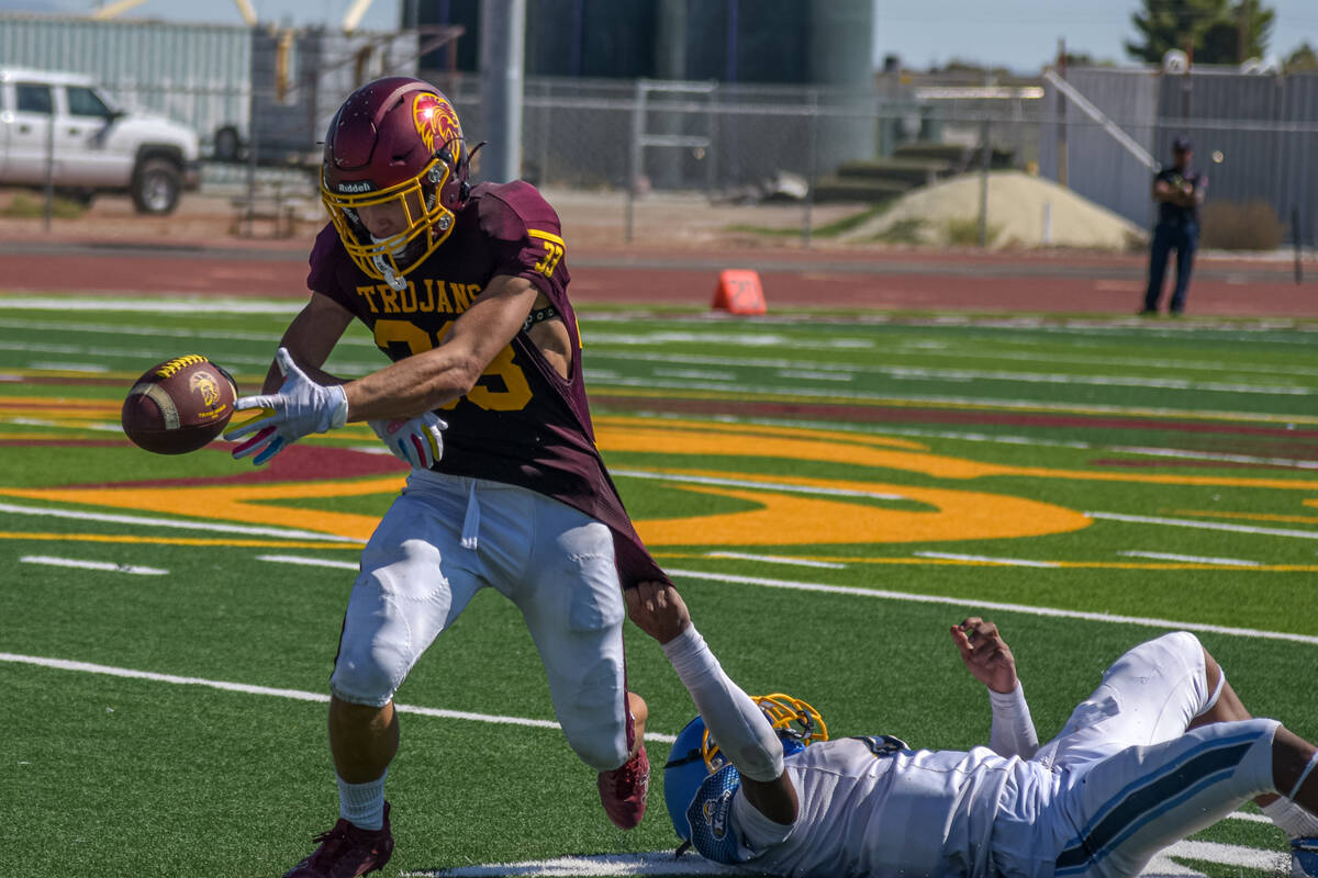 Trojans Austin Alvarez (33) fumbles the ball as a Democracy Prep player holds onto his jersey b ...