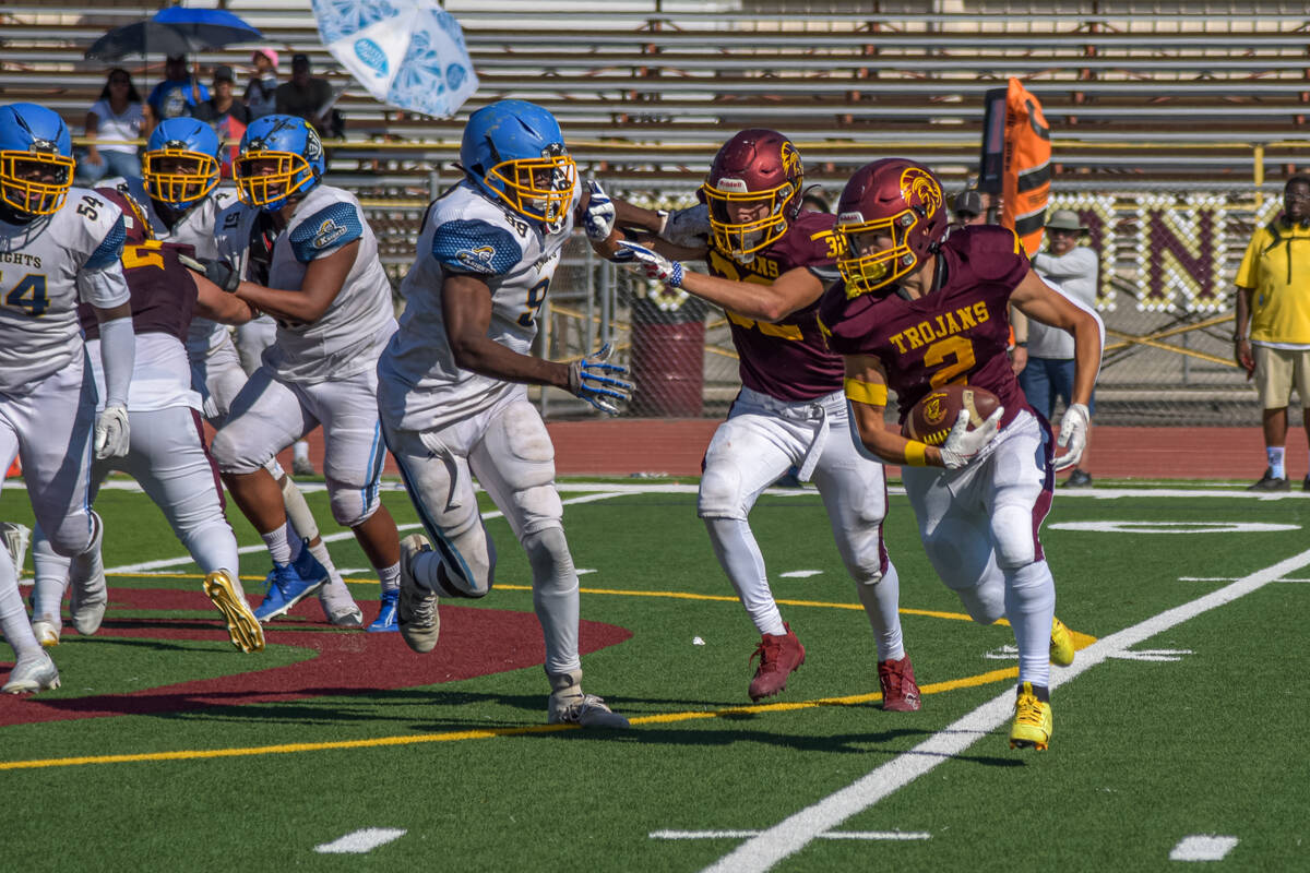 Trojans Carter Nygaard (2) carries the ball against Democracy Prep as Pahrump Valley players ho ...