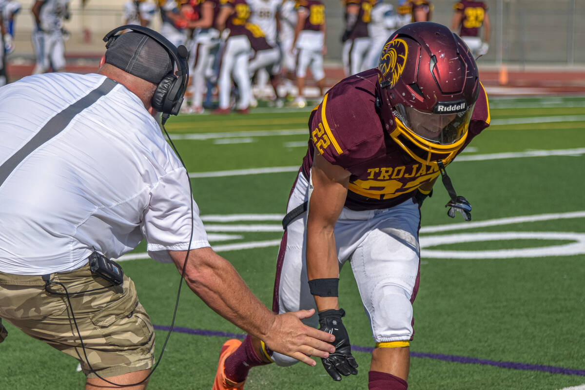 Trojans coach Tom Walker gives Benjamin De Santiago (22) a low-high five after a strong perform ...