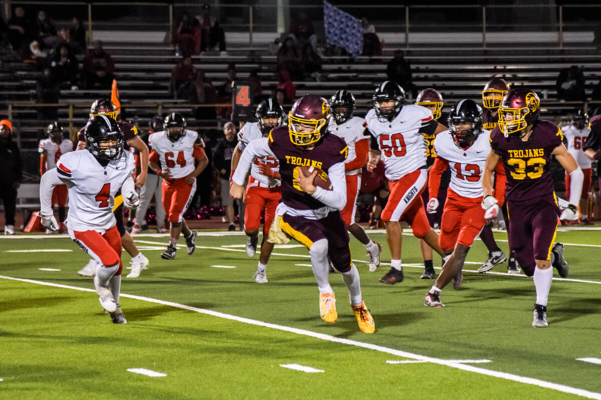 The Mater Academy East Las Vegas is after Trojans Kayne Horibe (8) (center) as he carries the b ...