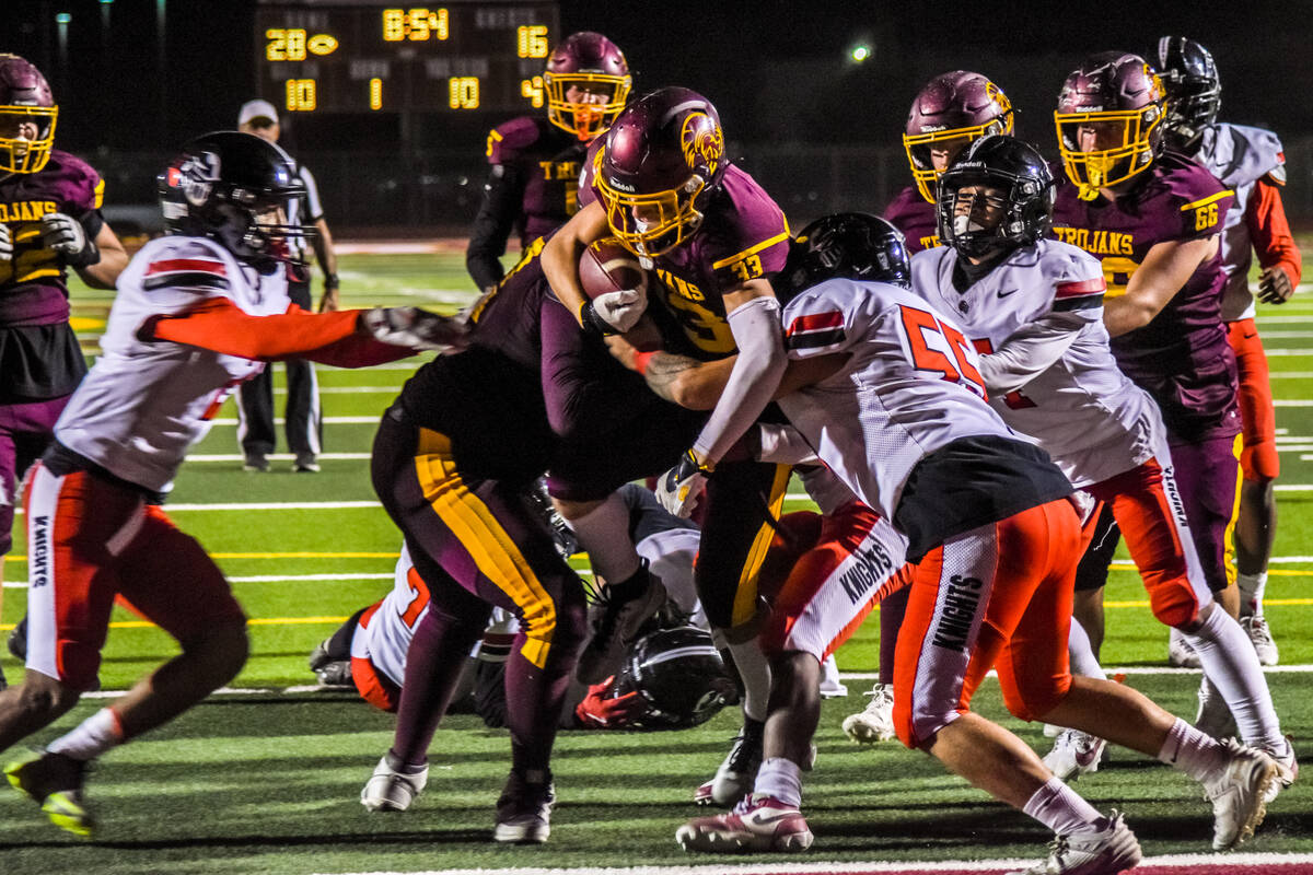 Trojans Austin Alvarez (33) (center) jumps over his defenders to get over the end zone line aga ...