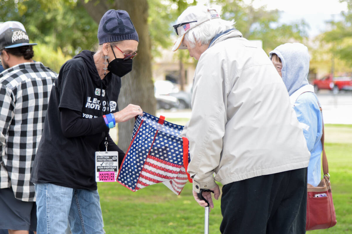 A non-partisan volunteer passes out candy to voters waiting in line to cast their ballots at th ...