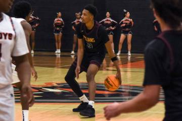 Trojans senior Tramaine Burras (13) dribbles the ball near the middle of the court against the ...