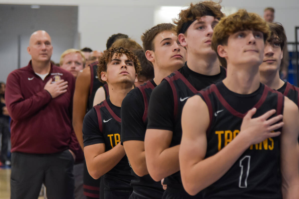 The Trojans basketball team lines up before a game against Coral Academy for the pledge of alle ...