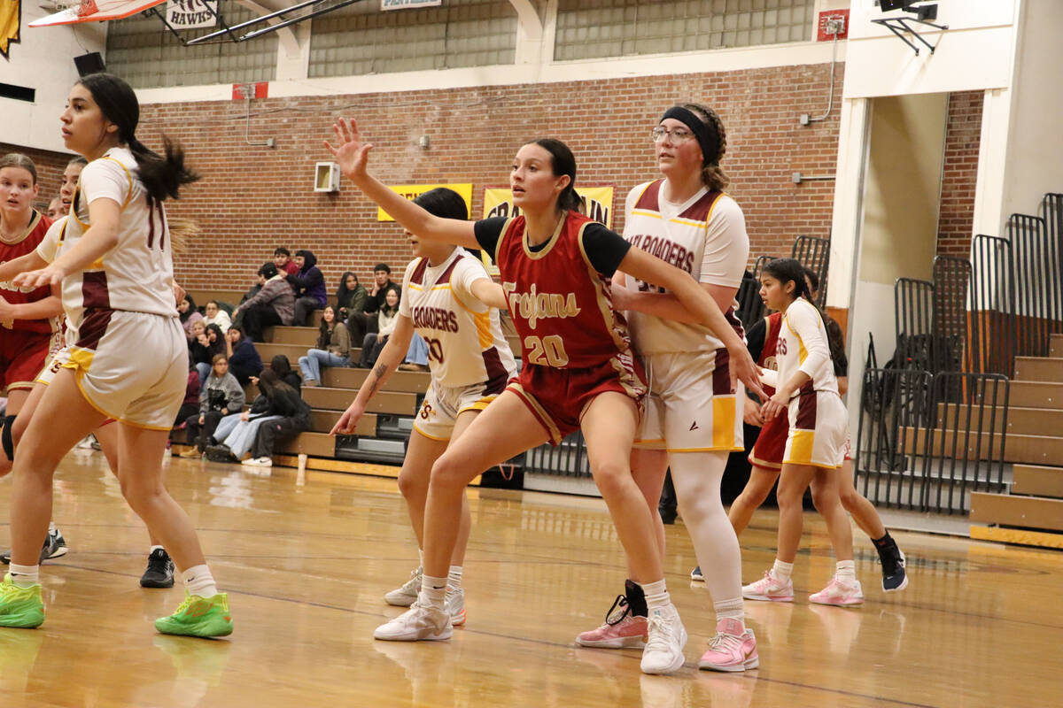 Trojans' senior Riley Saldana (20) signaling for the ball to her teammate as she is nearly unde ...