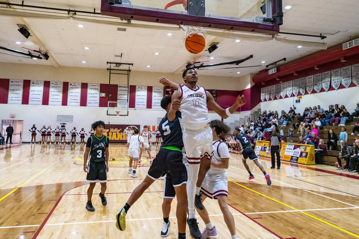 Trojans' Tramaine Burras (13) (center) scores a layup against SLAM in a week two league game on ...