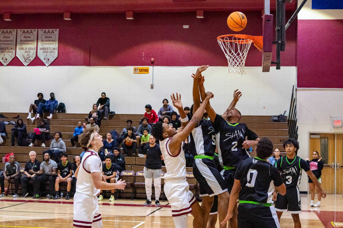 Pahrump Valley Trojans' boys basketball team watches the ball as Tramaine Burras (13) (center) ...