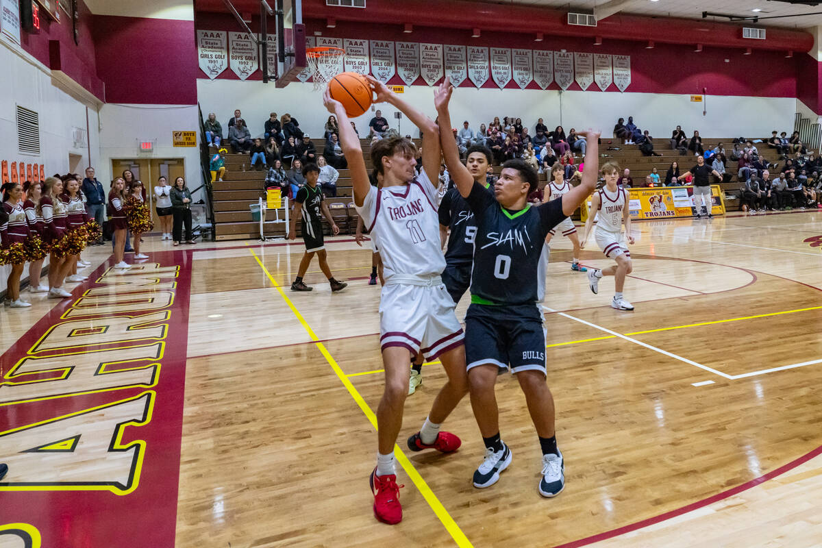 Trojans' Aydon Veloz (11) pulls the ball back against two SLAM players attempting to take the b ...