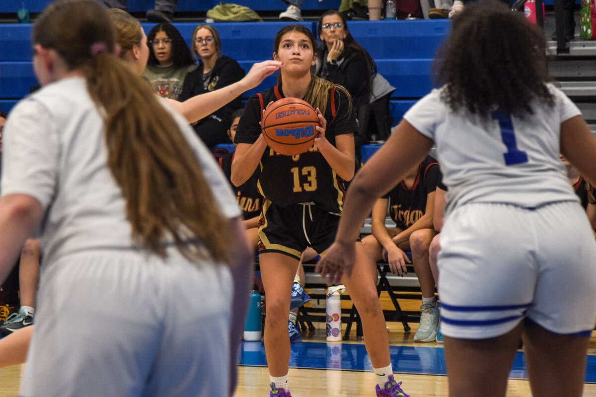 Trojans’ Ryleigh Denton (13) sets up to shoot a three-point shot against the Coral Acade ...