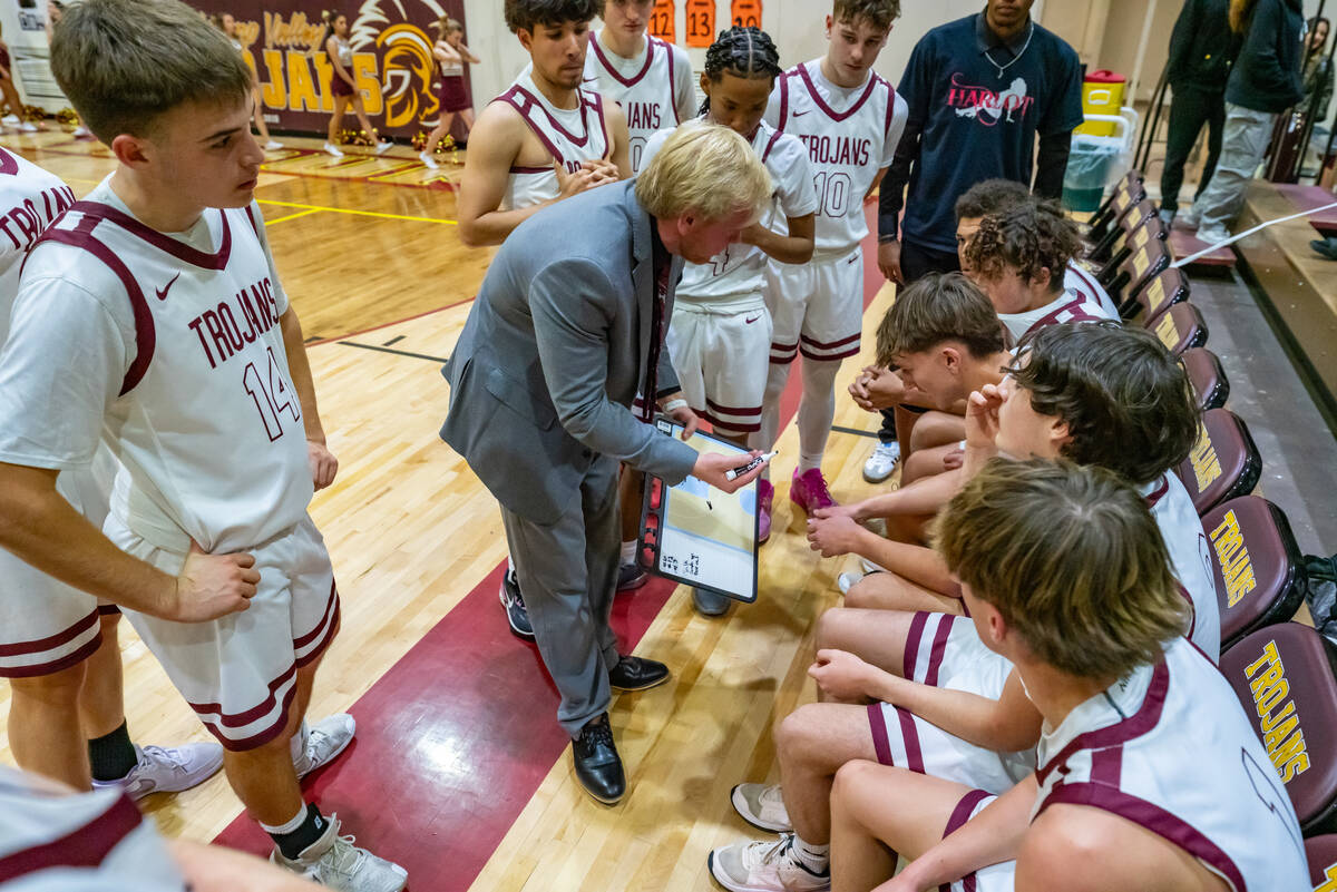 Trojans head coach Braydon Preston (center) talks to his team as they are behind in the game ag ...