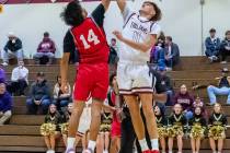 Trojans junior Aydon Veloz (11) (right) and Dragons freshman Kobe Artadi (14) (left) both jump ...