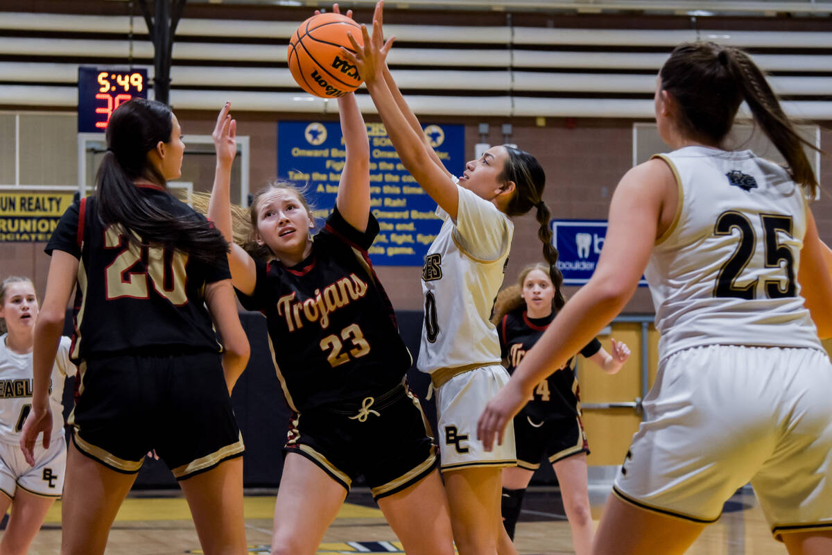 Trojans junior Nala Dalton (center) fights for ball possession against Boulder City in a league ...