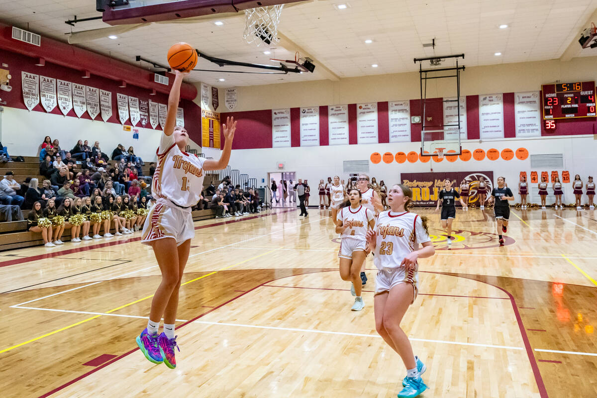 Trojans' senior Ryleigh Denton (13) (left) jumps in the air to score a two-point layup against ...