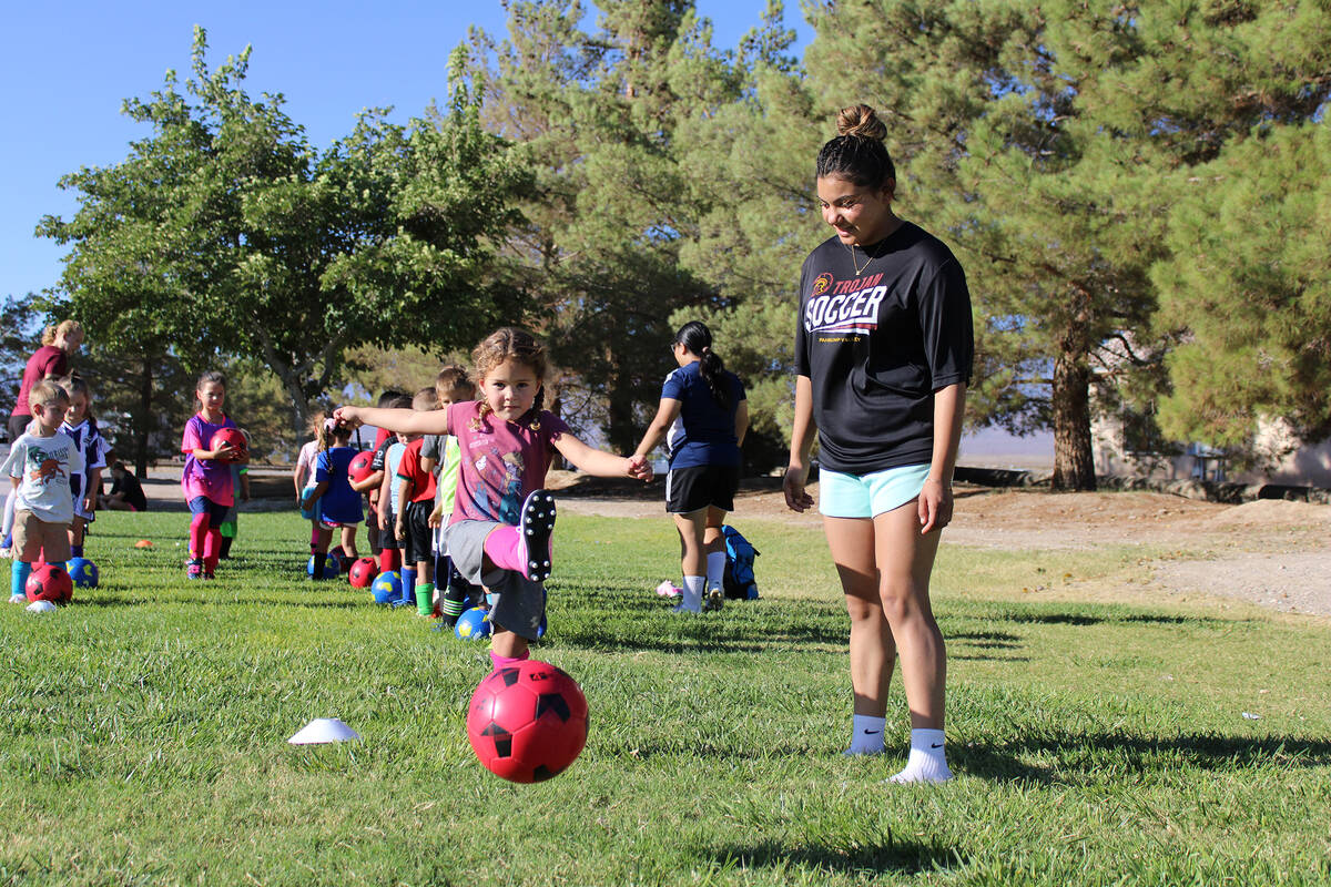 Youth camper Kenzie gives a forceful kick to the ball after being cheered on by PVHS girl's soc ...