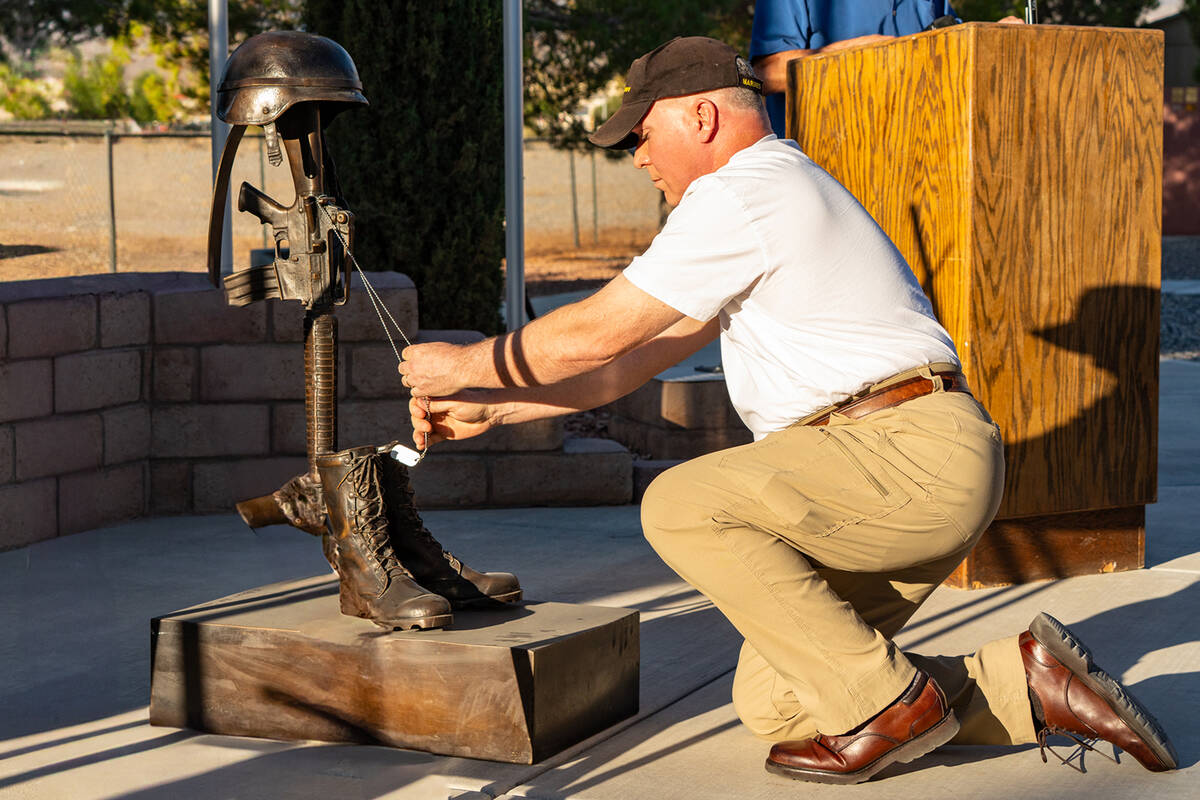 Maj. Tim Callahan kneels to place military ID/Dog Tags upon the Battlefield Cross statue at the ...