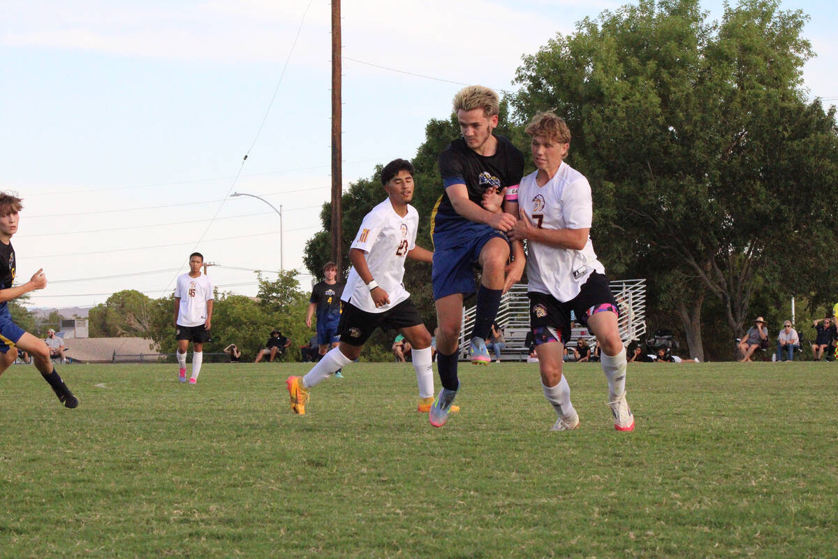 Pahrump Valley High School soccer junior midfielder TC Hone bodies a Boulder City defender to e ...