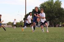 Pahrump Valley High School soccer junior midfielder TC Hone bodies a Boulder City defender to e ...