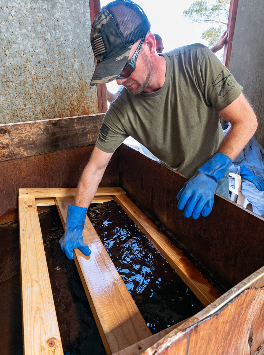 A Sleep in Heavenly Peace Bunks Across America volunteer dips a portion of a bed frame into sta ...