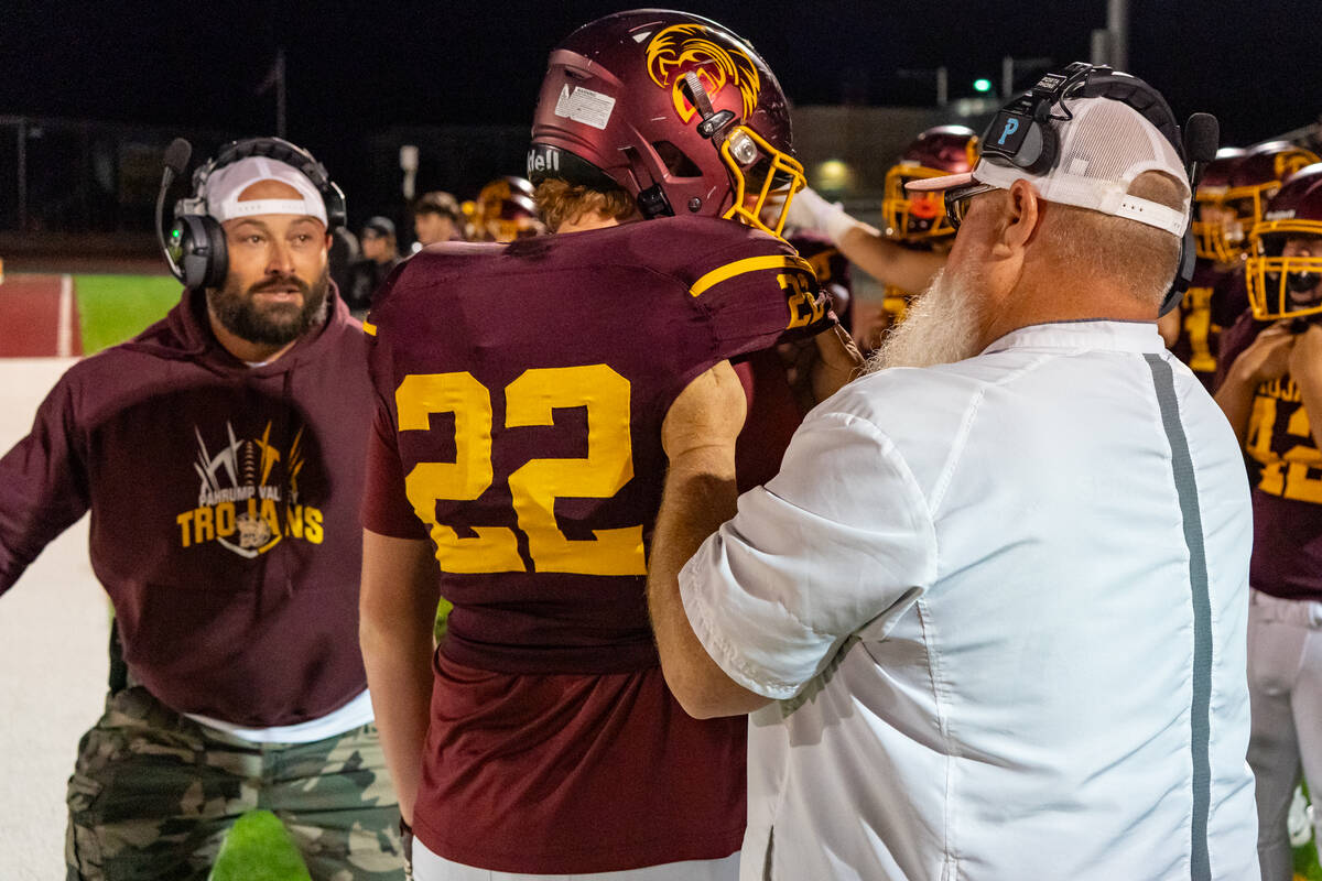 PVHS coaches Mike Colucci and Thom Walker help to assist in fixing junior DE/TE Paul Walker's u ...