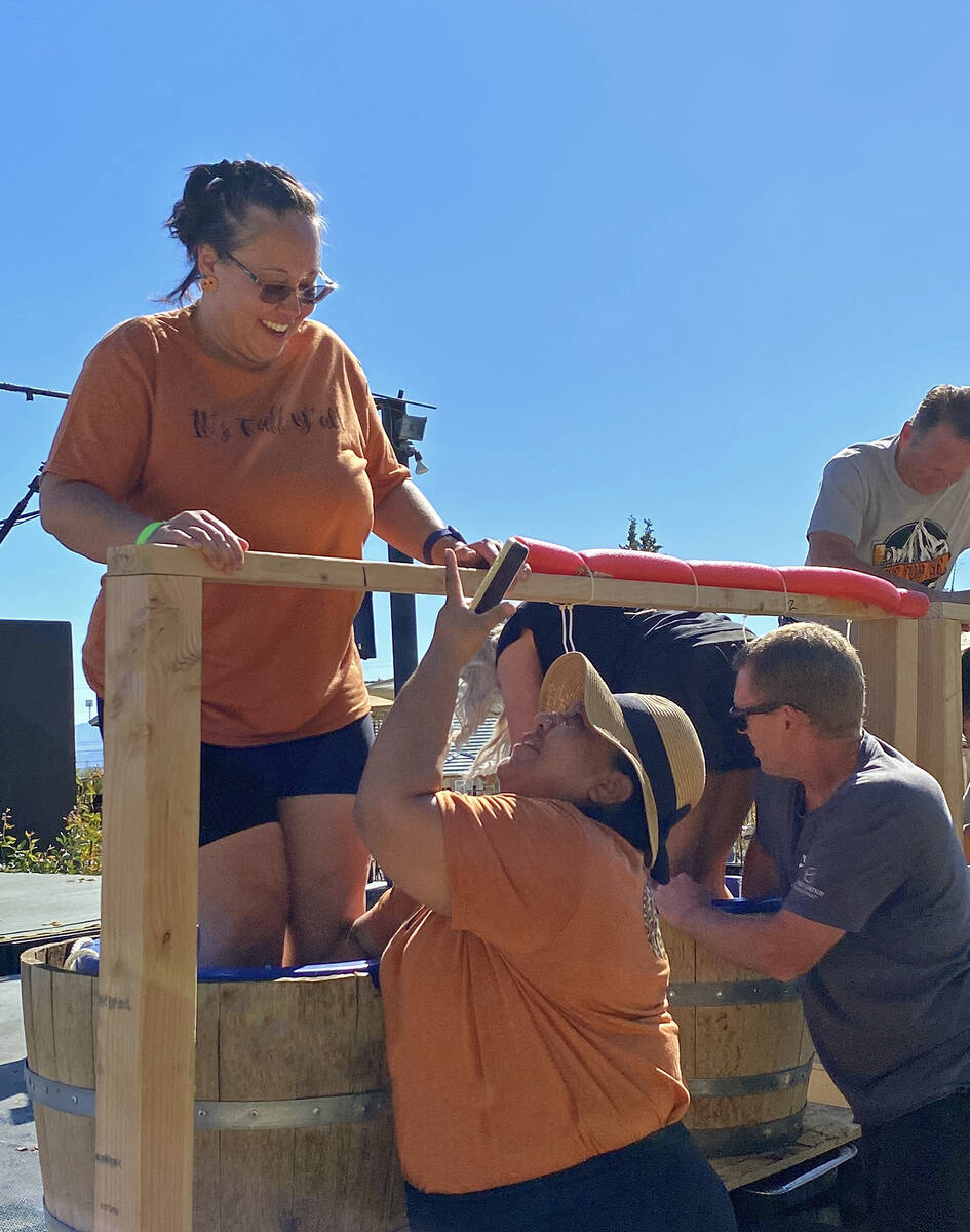 A Grape Stomp competitor takes a moment to capture a photo of her teammate as the two work in t ...