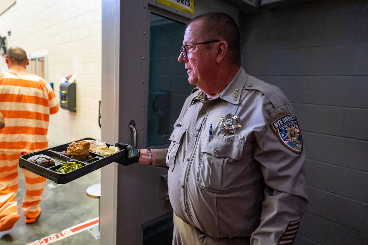 Sheriff Joe McGill hands out the dinner trays to each inmate in a pod. The jail can house 220 p ...