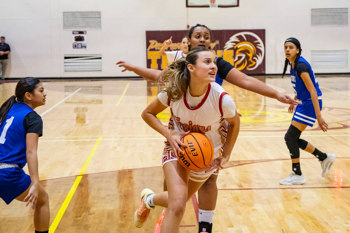 Pahrump Valley High School junior Riley Saldana drives through the top of the key in an attempt ...