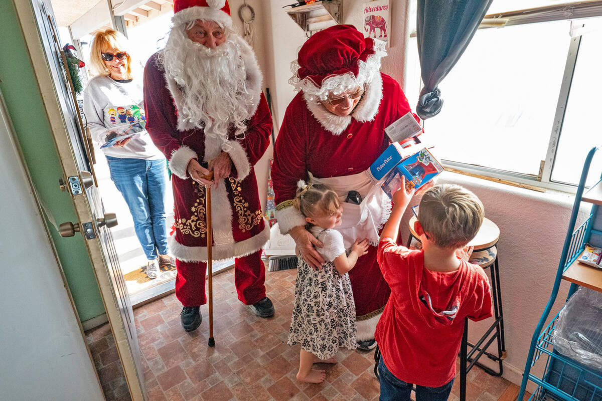 Five-year-old Noah Peterson and four-year-old Trina Peterson greet Santa and Mrs. Claus during ...