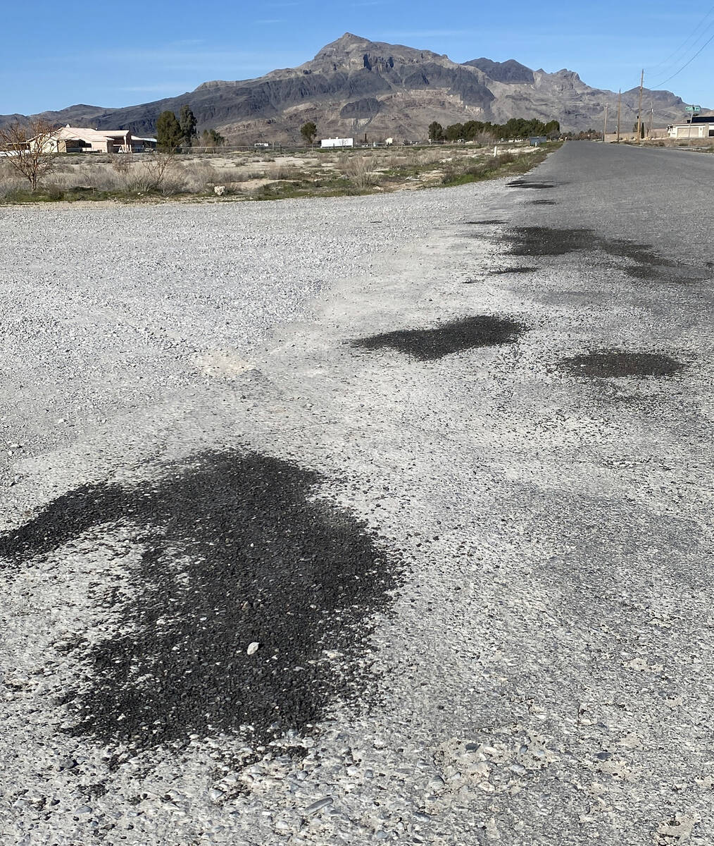 Dark black patches on the gray of the existing asphalt gives evidence to recent pothole repairs ...