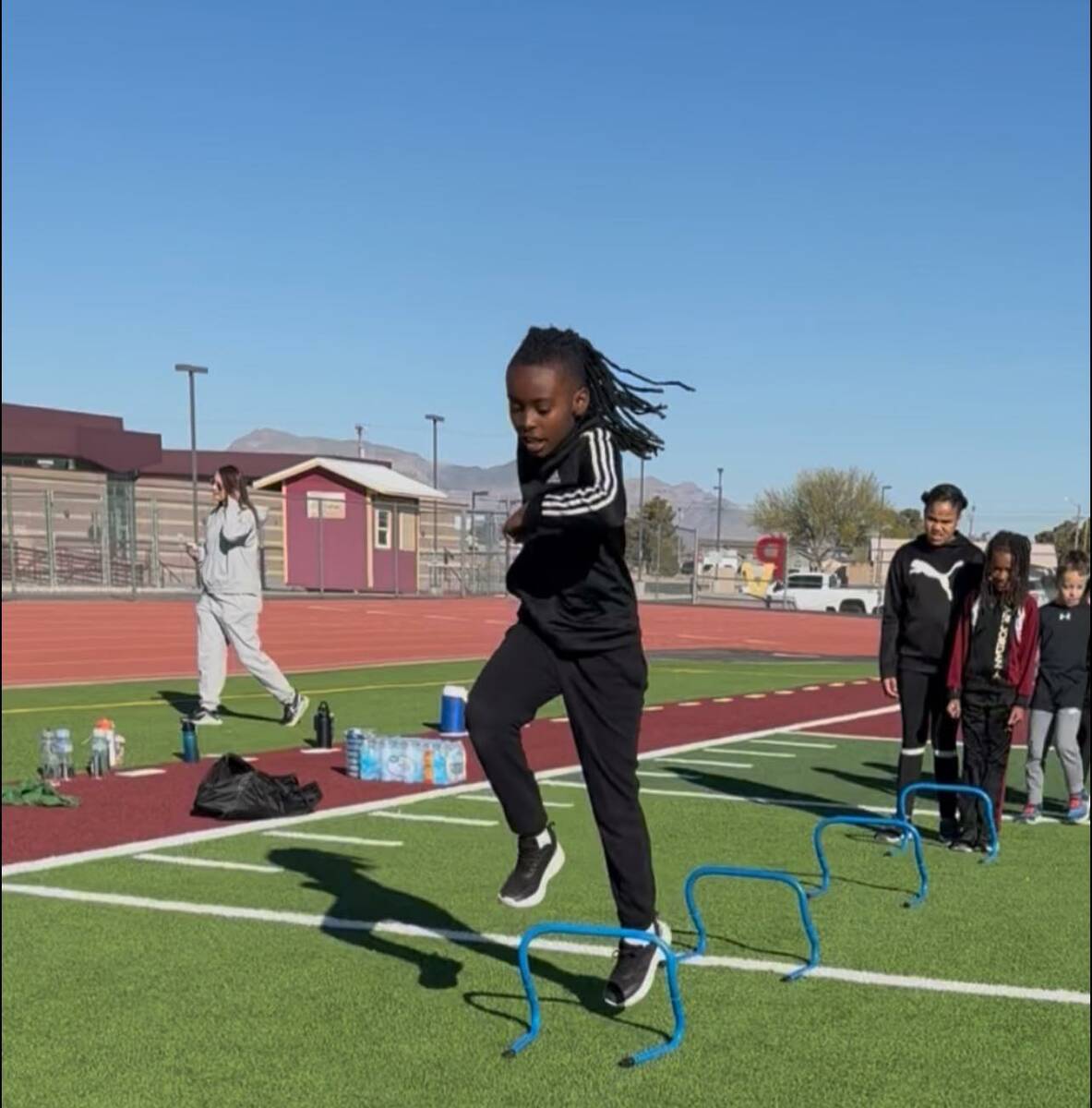 Local Pahrump youth athletes warm up on the football field at Pahrump Valley High School with d ...