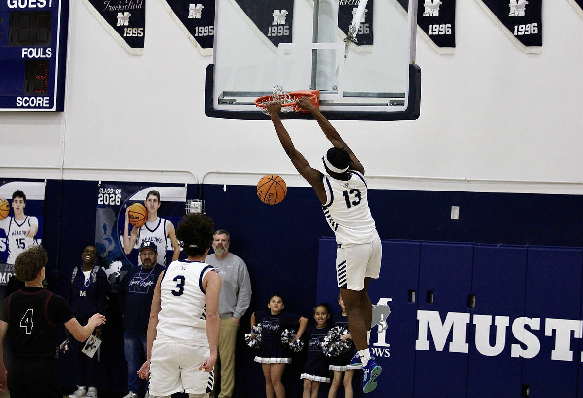 The Meadows' junior forward Uzo Nwapa hangs on the rim after his dunk on the Trojans during the ...