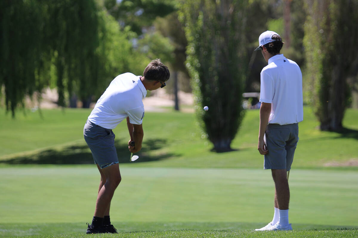 Pahrump Valley High School senior Cayden Cowley chips a shot next to teammate senior Caden Bris ...