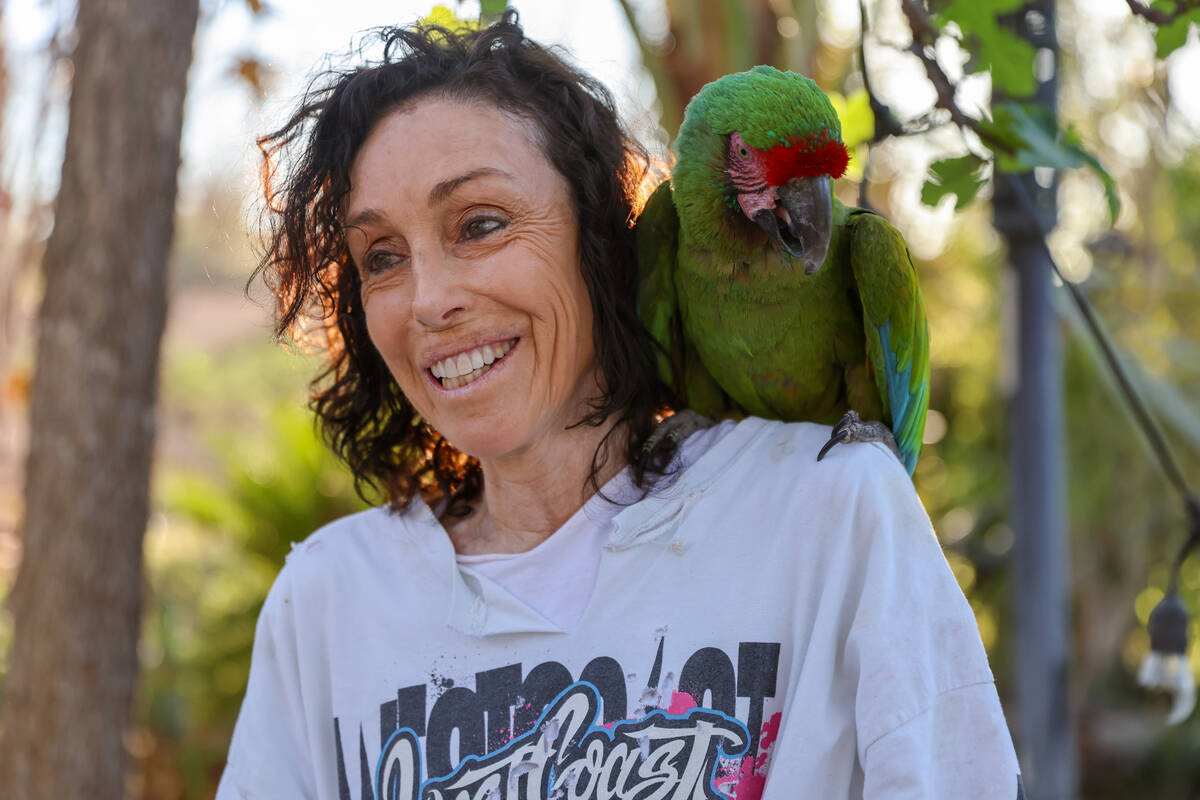 Heidi Fleiss, with a macaw named Gin perched on her shoulder, stands in her backyard and reflec ...