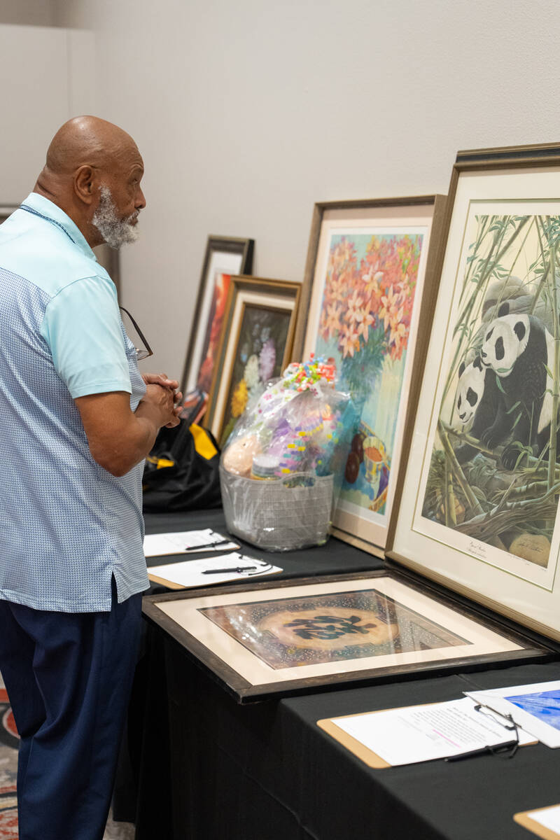 An Art for Recovery attendees admires a painting featuring playful pandas as he browses the ite ...