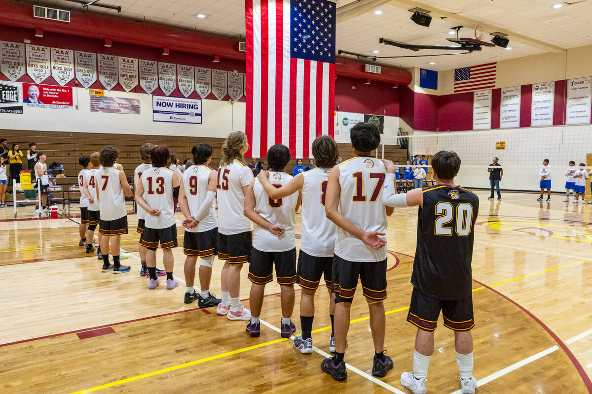 The Trojans varsity boys volleyball program lines up for the Pledge of Allegiance prior to the ...