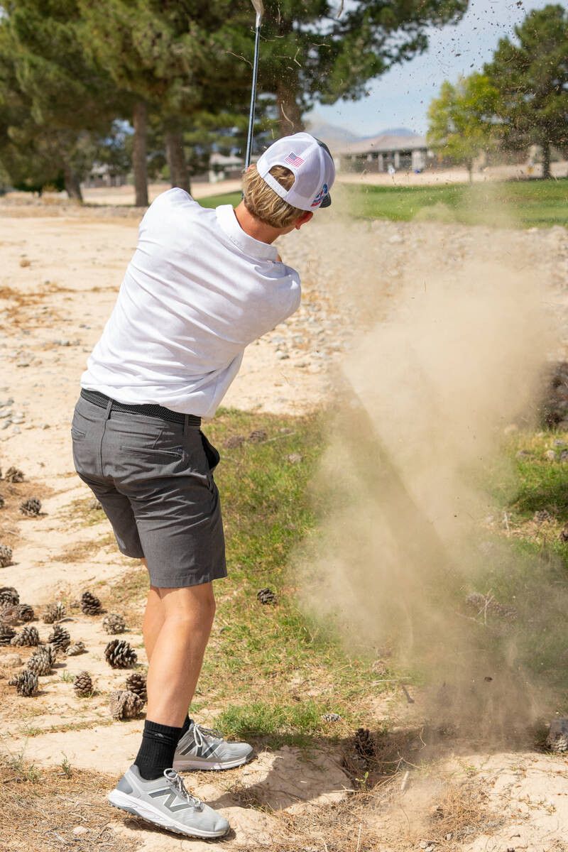 Pahrump Valley High School junior TC Hone expels a ball out of the sand bunker during the Troja ...