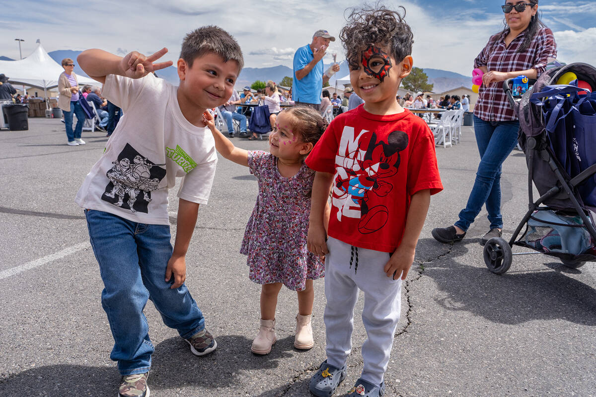 A trio of youngsters poses for a quick photo to show off their face paintings during the Desert ...