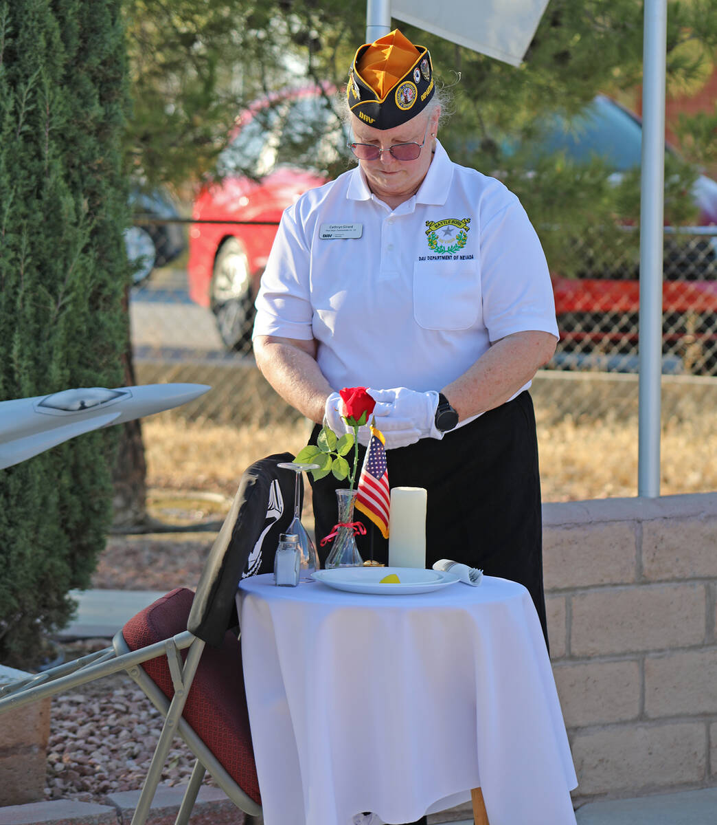 Disabled American Veteran Cathy Girard bows her head before the POW/MIA table, a display in whi ...